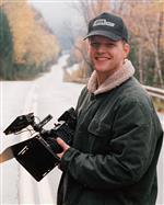 Dylan standing on aa road holding a cinematic camera