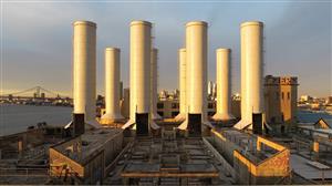 Warm sunlight hits painted smoke stacks on the Delaware River with the B.F> bridge in the distance